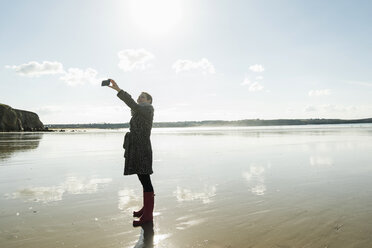 Frankreich, Bretagne, Finistere, Halbinsel Crozon, Frau macht ein Selfie am Strand - UUF006661