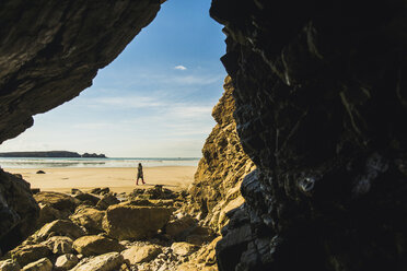 Frankreich, Bretagne, Finistere, Halbinsel Crozon, Frau bei Strandspaziergang von Felshöhle aus gesehen - UUF006674