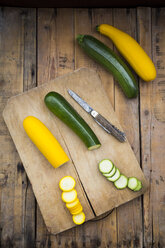 Gelbe und grüne Zucchini im Ganzen und in Scheiben geschnitten auf Holz - LVF004608