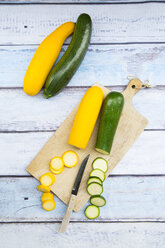 Gelbe und grüne Zucchini im Ganzen und in Scheiben geschnitten auf Holz - LVF004611