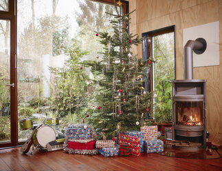 Weihnachtsgeschenke unter dem Weihnachtsbaum neben dem gemütlichen Kamin - RHF001294