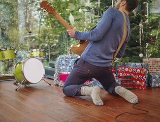 Mann spielt E-Gitarre vor einem Weihnachtsbaum - RHF001298