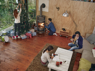 Freunde bereiten sich im gemütlichen Wohnzimmer auf den Weihnachtsabend vor - RHF001302