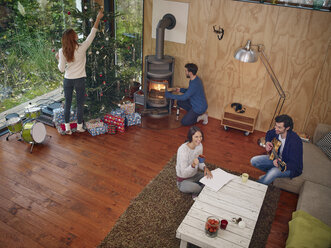 Freunde bereiten sich im gemütlichen Wohnzimmer auf den Weihnachtsabend vor - RHF001303