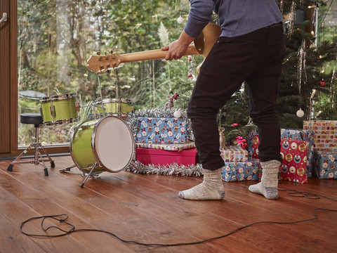 Mann spielt E-Gitarre vor einem Weihnachtsbaum, lizenzfreies Stockfoto