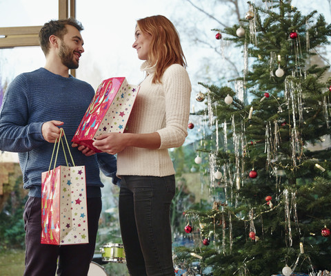 Ehepaar vor Weihnachtsbaum stehend, lizenzfreies Stockfoto