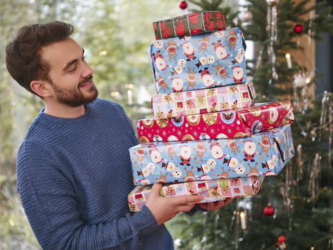Mann trägt Stapel von Weihnachtspaketen, lizenzfreies Stockfoto