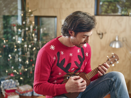 Mann spielt Ukulele vor einem Weihnachtsbaum - RHF001342