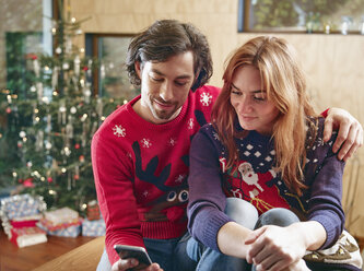 Glückliches Paar macht Selfie vor dem Weihnachtsbaum - RHF001344