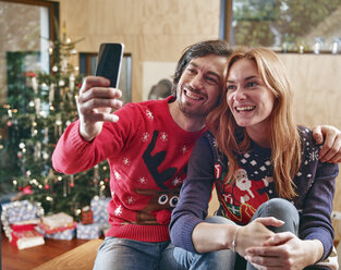 Glückliches Paar macht Selfie vor dem Weihnachtsbaum - RHF001345