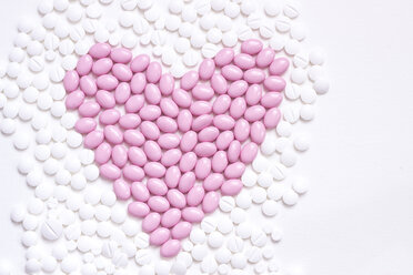 Pink heart shaped of pills in between white tablets - CMF000359