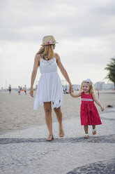 Brasilien, Rio de Janeiro, Mutter und Tochter gehen am Strand der Copacabana spazieren - MAUF000256