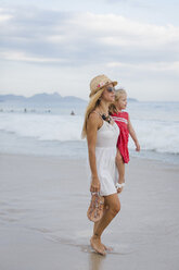 Brasilien, Rio de Janeiro, Mutter trägt Tochter am Strand der Copacabana - MAUF000268