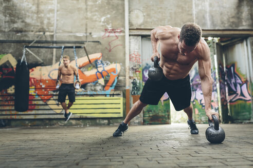 Junger Mann beim Workout mit Kettlebells - MADF000851