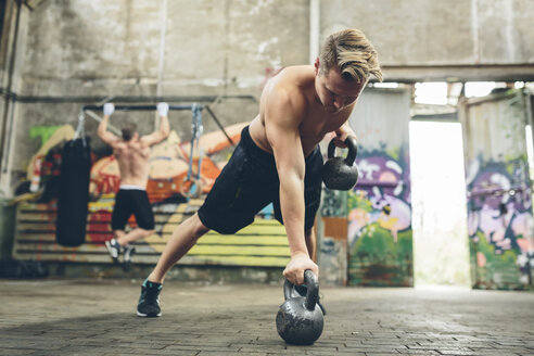 Junger Mann beim Workout mit Kettlebells - MADF000853