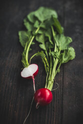 Whole and sliced red radish on dark wood - DEGF000671