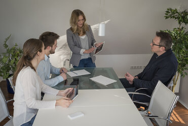 Woman leading a presentation with digital tablet in conference room - PAF001575