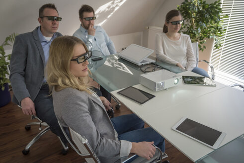 Vier Kollegen mit 3D-Brillen bei einer Präsentation mit Projektor im Konferenzraum - PAF001588