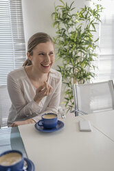 Lächelnde Frau bei einer Kaffeepause im Büro - PAF001593