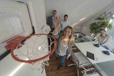 Happy woman playing basketball in conference room - PAF001598