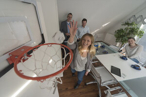 Glückliche Frau spielt Basketball im Konferenzraum - PAF001598