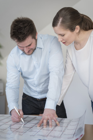 Junger Mann und Frau im Büro mit Blick auf den Kalender, lizenzfreies Stockfoto