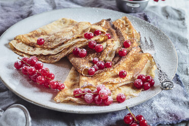 Crepes with red currents sprinkled with icing sugar on plate, close-up - SBDF002699