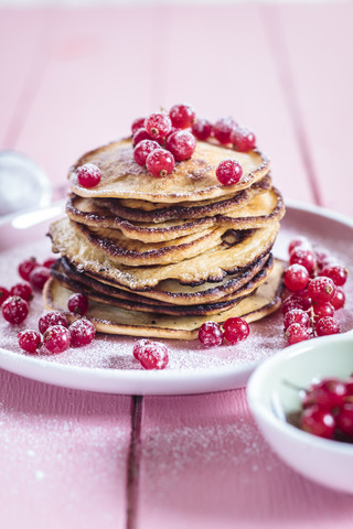 Stack of American pancakes with red currents sprinkled with icing sugar stock photo