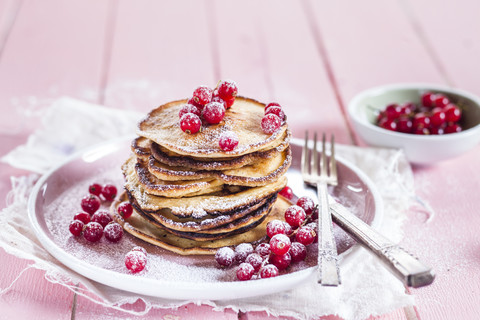 Stapel amerikanischer Pfannkuchen mit roten Johannisbeeren, bestreut mit Puderzucker, lizenzfreies Stockfoto