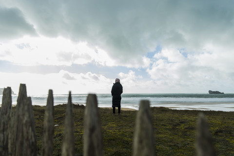 Frankreich, Bretagne, Finistere, Halbinsel Crozon, Frau steht an der Küste, lizenzfreies Stockfoto