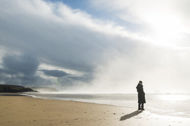 Frankreich, Bretagne, Finistere, Halbinsel Crozon, Frau steht am Strand - UUF006711