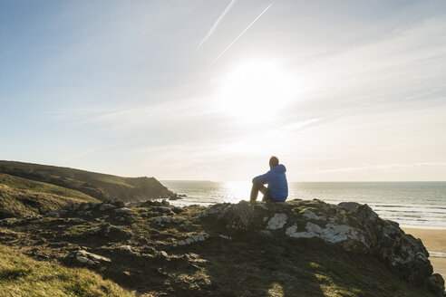 France, Bretagne, Finistere, Crozon peninsula, man sitting on rock at the coast - UUF006741