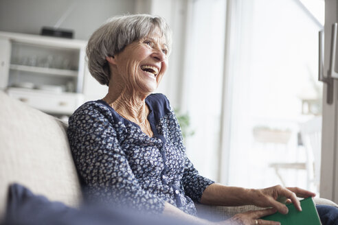 Portrait of happy senior woman sitting on couch at home - RBF004108