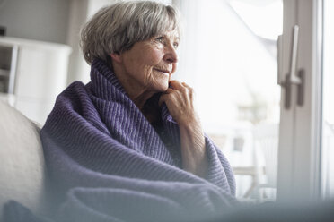 Porträt einer nachdenklichen älteren Frau, die zu Hause auf der Couch sitzt - RBF004111