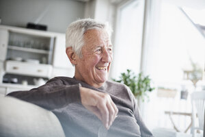 Porträt eines lachenden älteren Mannes, der zu Hause auf der Couch sitzt - RBF004114