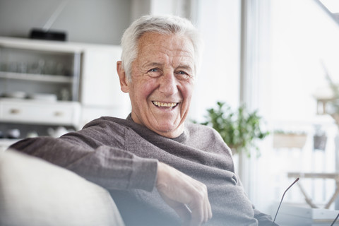 Portrait of happy senior man sitting on couch at home stock photo