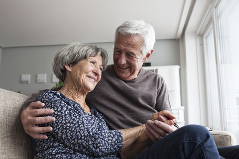 Happy senior couple sitting together on the couch at living room stock photo