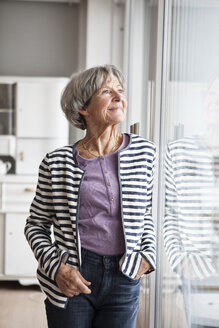 Porträt einer selbstbewussten älteren Frau, die durch ein Fenster schaut - RBF004144
