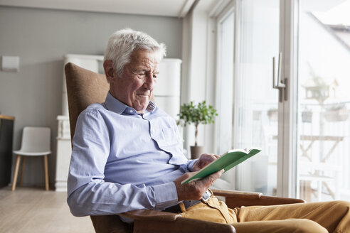 Porträt eines älteren Mannes, der zu Hause auf einem Sessel sitzt und ein Buch liest - RBF004154