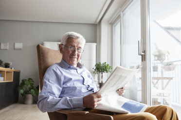 Porträt eines älteren Mannes, der zu Hause auf einem Sessel sitzt und Zeitung liest - RBF004173
