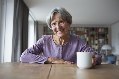 Porträt einer älteren Frau, die mit einer Tasse Kaffee am Tisch sitzt, lizenzfreies Stockfoto