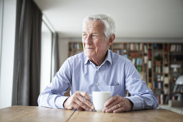 Portrait of pensive senior man sitting at table with cup of coffee looking through window - RBF004177