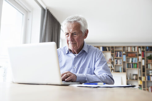 Porträt eines älteren Mannes, der am Tisch sitzt und einen Laptop benutzt - RBF004182