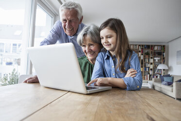 Großeltern und ihre Enkelin mit Laptop zu Hause - RBF004188