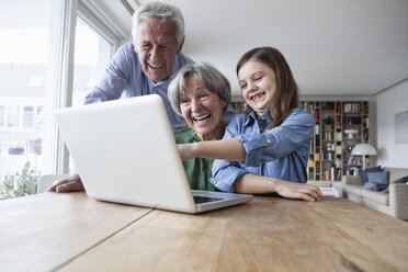 Großeltern und ihre Enkelin haben Spaß mit dem Laptop zu Hause - RBF004189