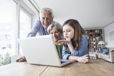 Großeltern und ihre Enkelin beim Skypen mit dem Laptop zu Hause - RBF004191