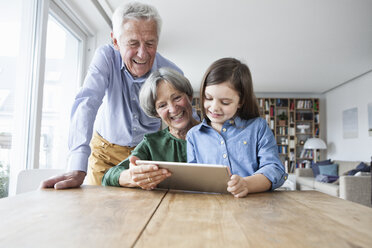 Großeltern und ihre Enkelin nutzen ein digitales Tablet zu Hause - RBF004192