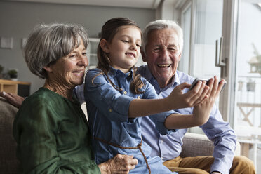 Little girl taking selfie with her grandparents at home - RBF004203