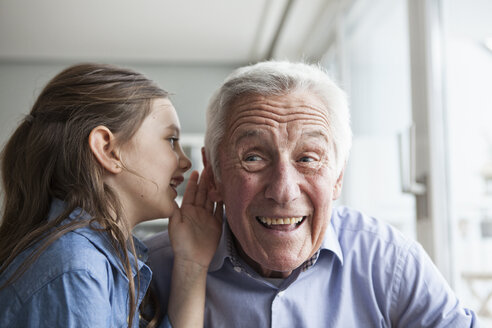 Enkelin flüstert ihrem Großvater etwas ins Ohr - RBF004218