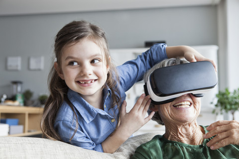 Eine ältere Frau und ihre Enkelin haben Spaß mit einer Virtual-Reality-Brille zu Hause, lizenzfreies Stockfoto